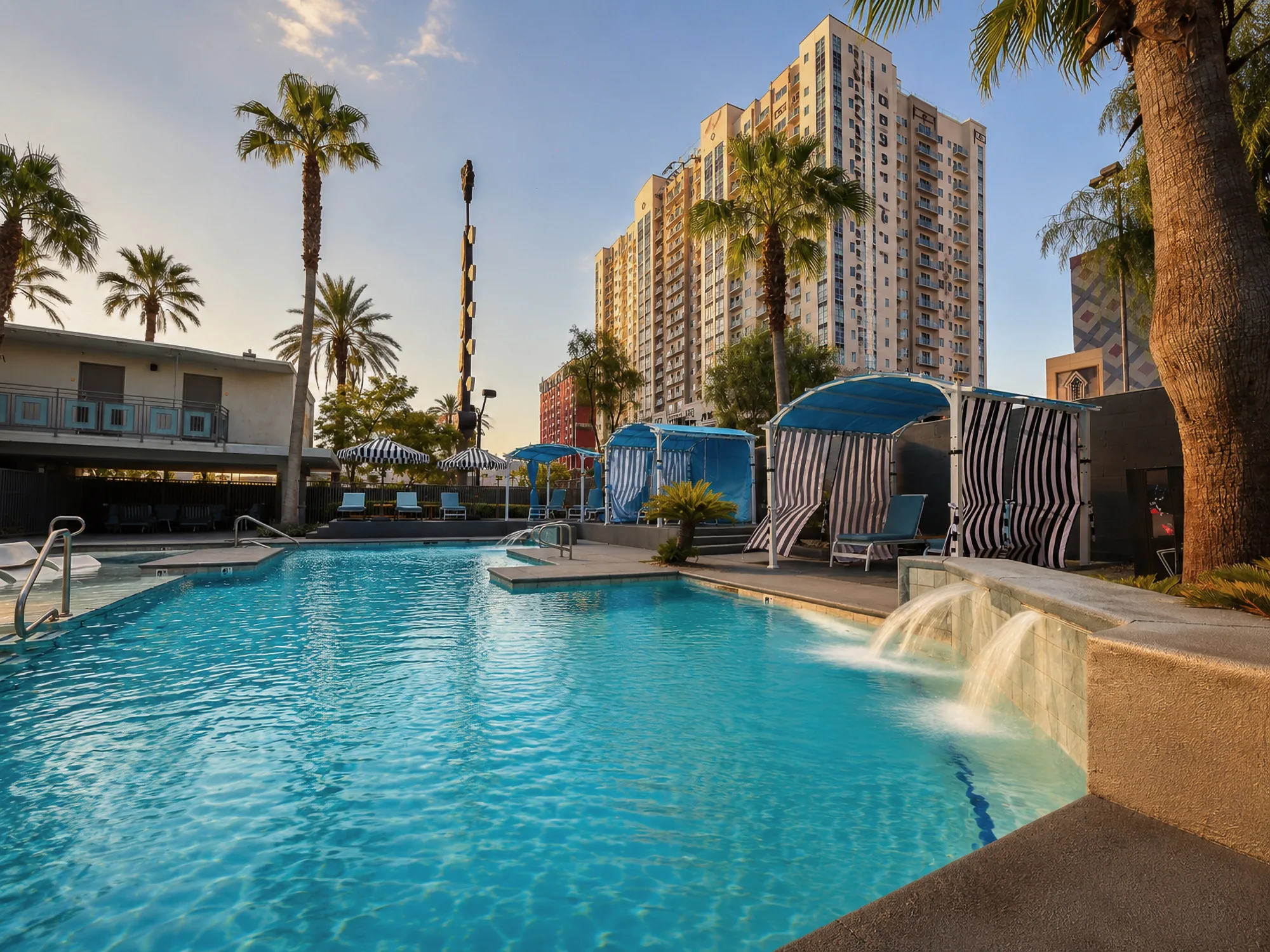 Oasis pool with striped cabanas and downtown towers behind